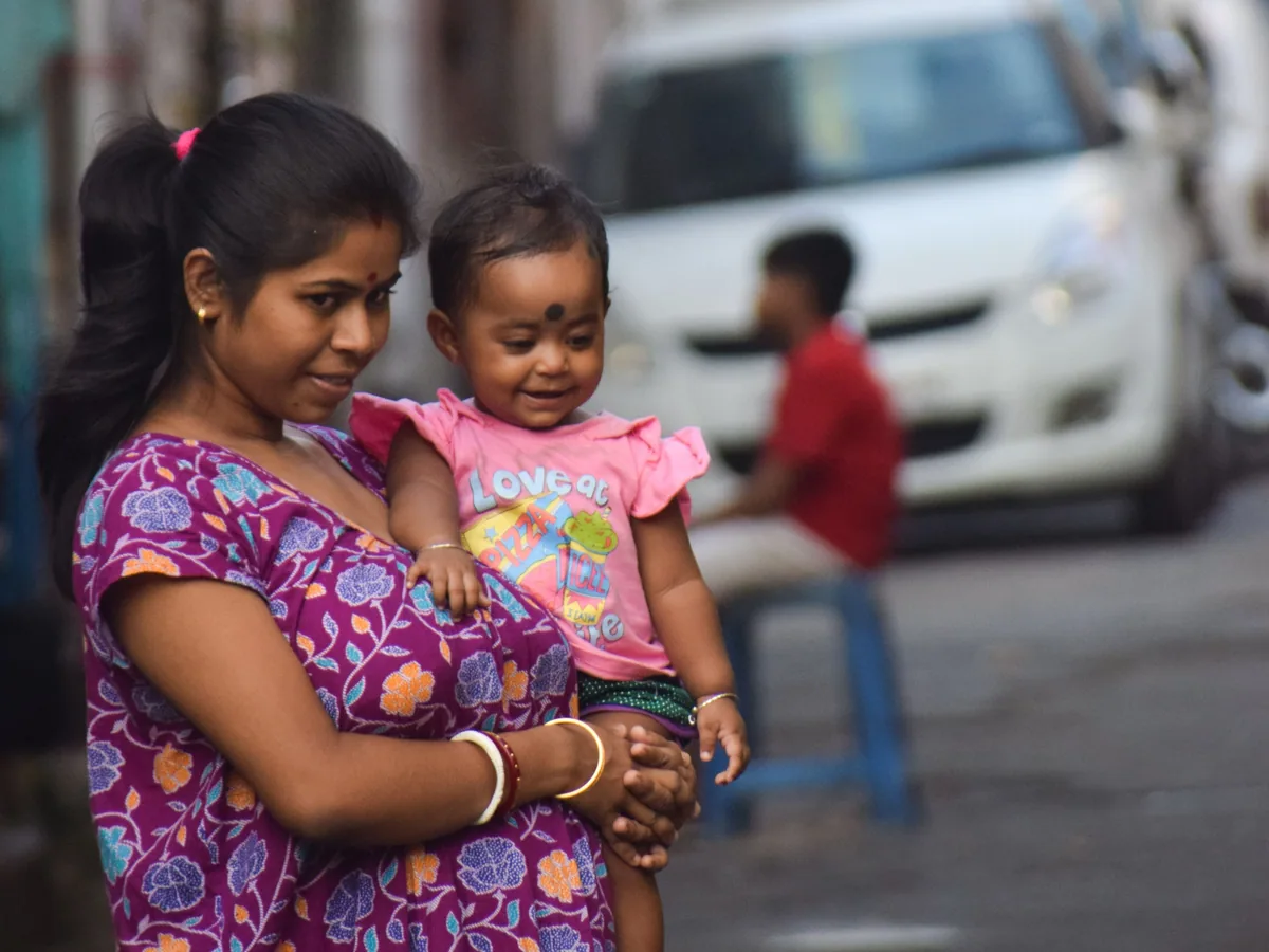 A mother holding her smiling toddler on a Kolkata street, a representative family photograph